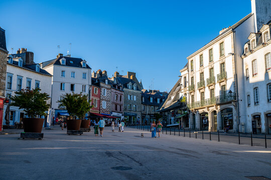 People walk and shop in a busy street with buildings under blue sky in France