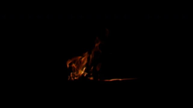 A small isolated fire with bright orange flames flickering intensely against a solid black background.