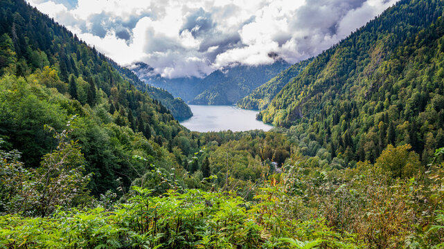 View from the overlook of Ritsa Lake showing mountains and lush forests in a natural landscape with clouds above