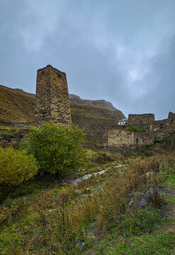 Exploring the remains of Kamunta village in North Ossetia, Russia, showing old stone structures under a cloudy sky