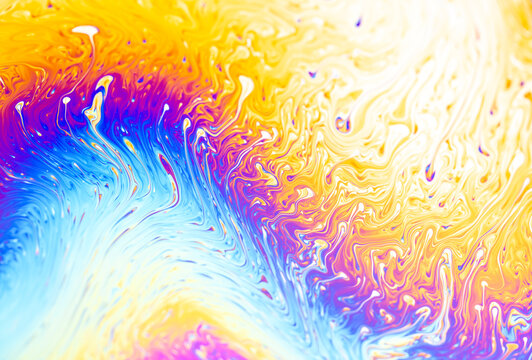Vibrant iridescent soap bubble surface with swirling patterns of blue, purple, and yellow