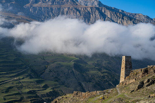 Old watchtower stands tall against mountains and clouds in North Ossetia, Russia