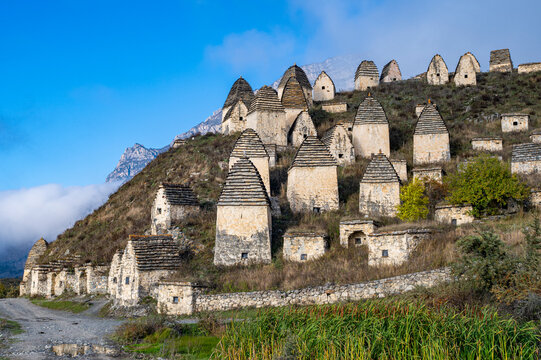 Exploring ancient burial structures in Dargavs, a historical site in North Ossetia, Russia, surrounded by mountains and greenery
