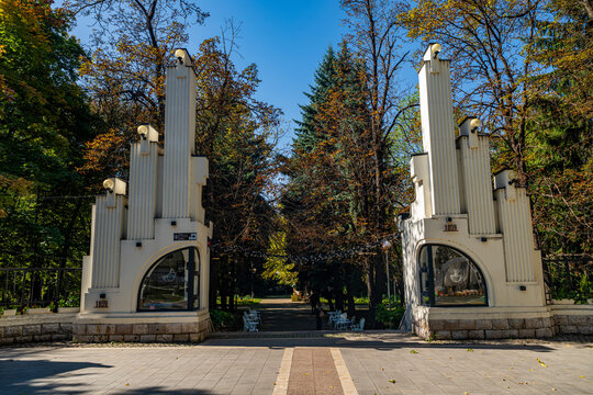 Historic entrance to a park in Vladikavkaz with tall columns and trees in the background during a bright day