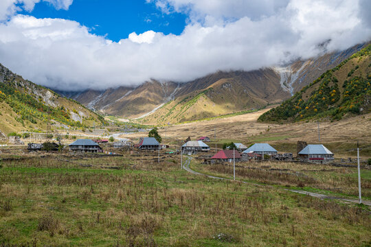 Mountain village situated in the mountains of South Ossetia, Russia with houses and open land during a cloudy day