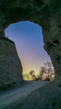 Giant rock arch stands in the Chechen mountains against a sunset sky in the Caucasus region of Russia