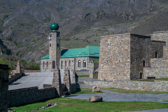 Exploration of the central mosque in Itum-Kali with stone structures and mountains in the background