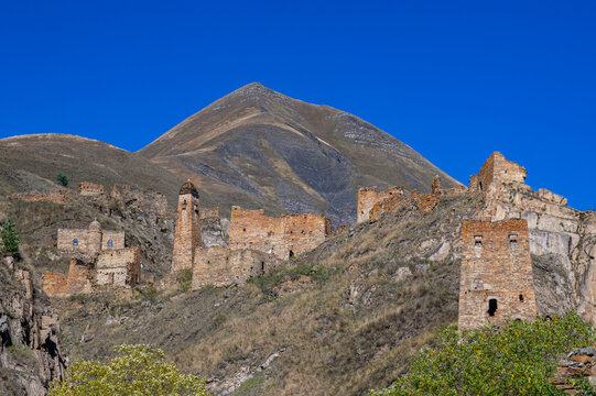 Exploring an abandoned mountain village in Chechnya with ruins and a distant mountain in the sky