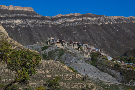 Mountain village built on a hillside under clear blue sky in Dagestan, Russia, with rocky mountains in the background