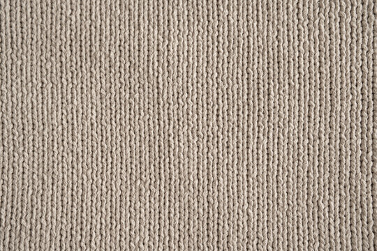 Knit pattern in beige wool fabric. Fine woven cotton texture for a decorative background. Close-up. Top view.