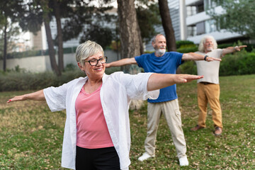 Obraz premium Senior healthy people doing yoga outdoors, at the urban park
