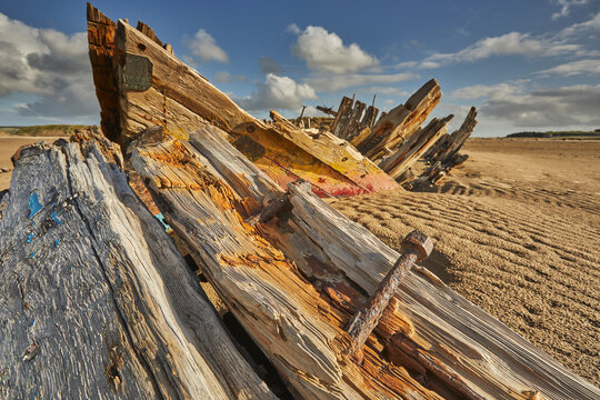 Disintegrating wreck rests on the beach at Crow Point in Devon near Barnstaple under a cloudy sky