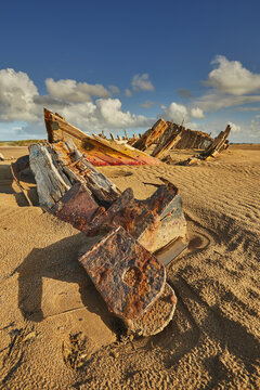 Wreck of a boat on sand at Crow Point near Barnstaple in Devon on a sunny day with clouds