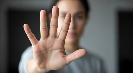 Obraz premium Close up of a raised hand palm facing camera with blurred female face