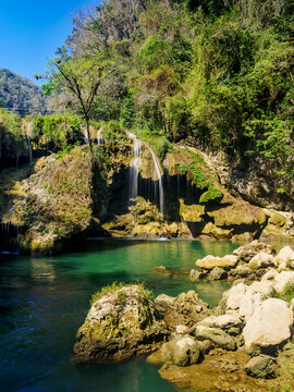 Cahabon River waterfall flows through rocks and greenery in Semuc Champey Natural Monument in Guatemala