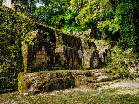 Ruins of Group G at Acanaladuras Palace in Tikal show remnants of ancient structures surrounded by jungle greenery
