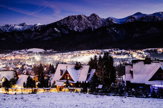 Winter night view of Zakopane and the High Tatras in Poland with snow-covered rooftops and mountain peaks