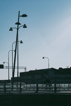 Streetlight silhouettes in Stockholm, Sweden stand above a bridge, skyline and clear sky as urban transportation layers fade into a quiet road