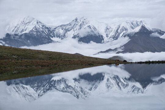 Snow-covered mountain peak reflected in lake under evening light in western Sichuan, China