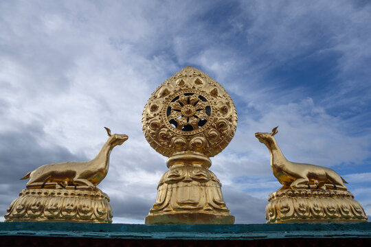 Golden Dharma wheel with deer on top of Songzanlin Monastery against a dramatic sky in Yunnan China