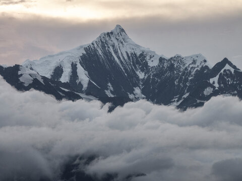 Snow-covered peaks rise above clouds in Meili Mountains during evening light in Yunnan