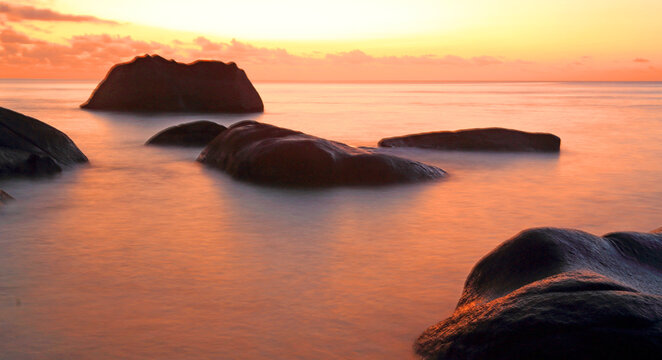 Sunset at Beau Vallon beach, with rocky formations and calm waters in Seychelles