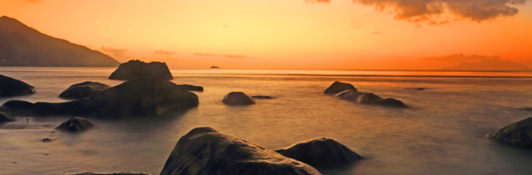 View of calm waters and rocks during sunset at a beach in Seychelles