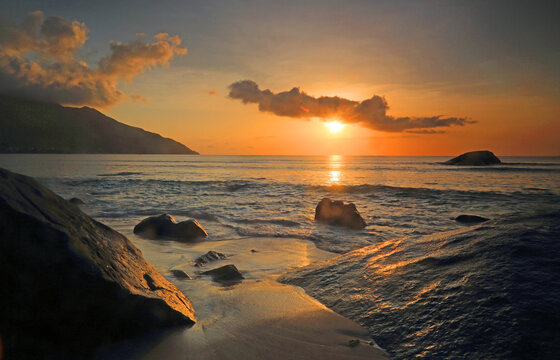 Sunset at Beau Vallon beach with waves gently lapping against rocks in Mahe, Seychelles