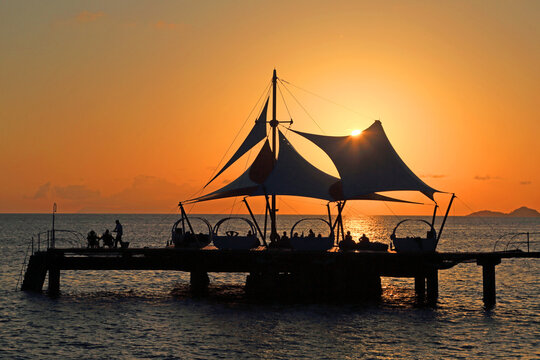 Sunset over water at Coco de Mer hotel near Praslin, Seychelles, with silhouettes and shadows on the dock