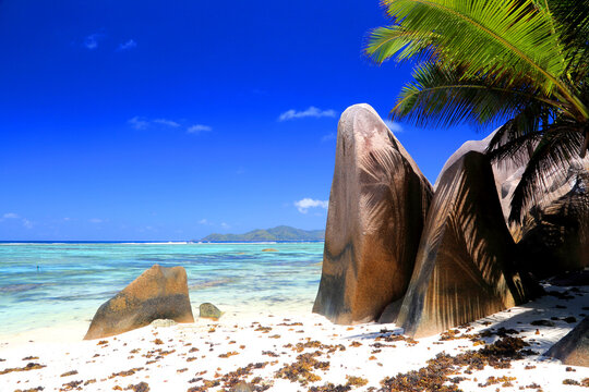 Crystal clear water and unique rock formations along a beach in Seychelles during bright sunny weather