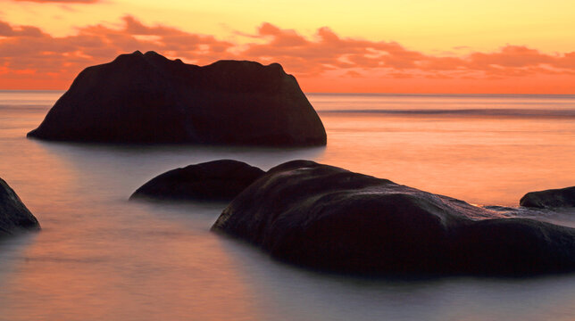 Dusk over rocks at Beau Vallon beach on Mahe island in Seychelles during sunset