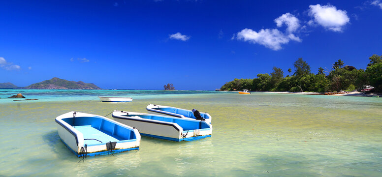 Boats rest on the clear water of Anse Source dArgent beach at La Digue during a sunny day in Seychelles, showcasing the landscape and natural beauty