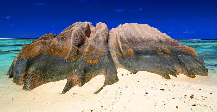 Rock formation on the beach with clear water and blue sky at a sunny day in La Digue, Seychelles