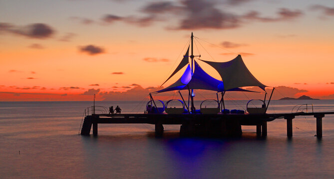 Sunset view from pier at Coco de Mer resort on Praslin Island with silhouettes of people against the sky