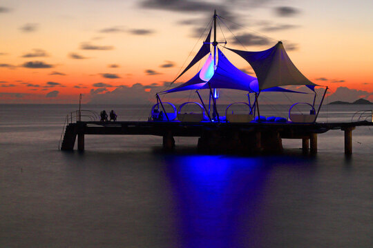 Sunset view over water with a pier and structure at Coco de Mer resort on Praslin Island in Seychelles