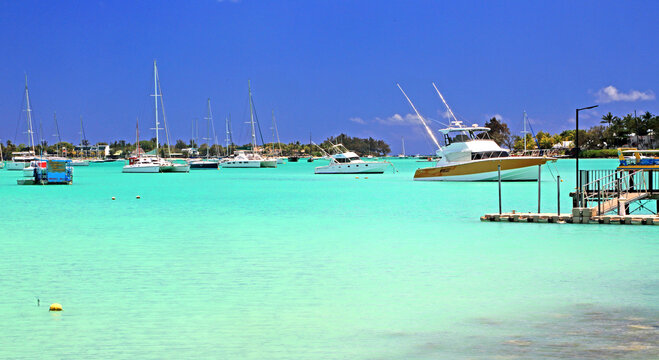 Sailboats and yachts are anchored at Grand Baie in northern Mauritius during a sunny day on the water