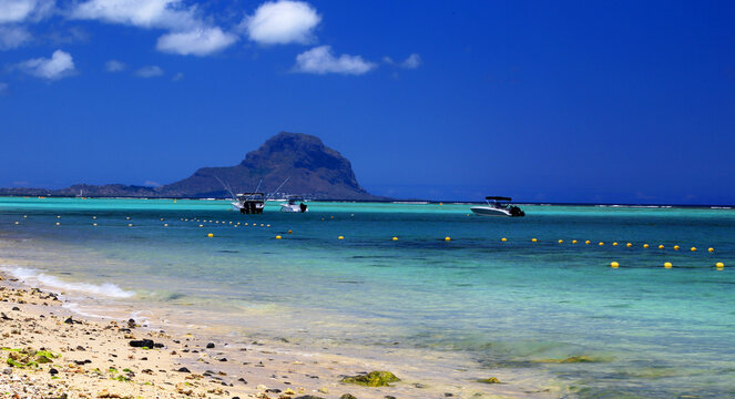 View of Le Morne from Flic en Flac beach in Mauritius with boats and clear water on a sunny day