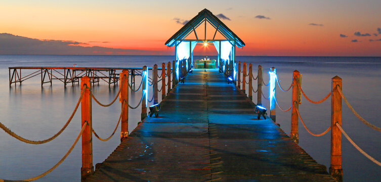 Sunset view from a wooden pier with lights over the water in Mauritius during evening hours