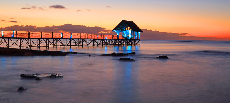 Sunset view over a pier with lights at Pointe aux Piments in Mauritius