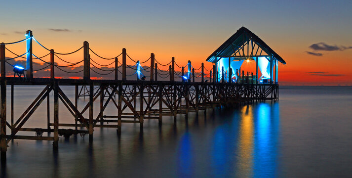 Sunset view over a pier with lights shining, showcasing the beauty of the sky and water at Pointe aux Piments in Mauritius