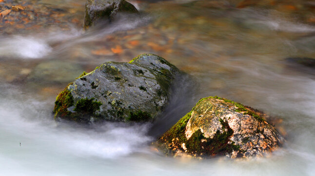 Stream flows gently over rocks in Buttermere village during autumn in Cumbria, Lake District, United Kingdom