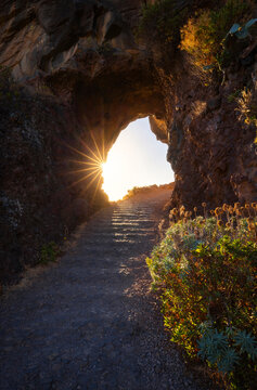 Sunset shining through a rock tunnel near Ponta do Sol in Madeira region of Portugal