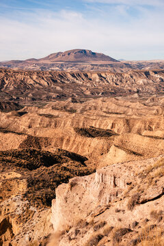 Eroded cliffs and winding ravines in a desert landscape with mountains in the distance in Granada, Andalusia