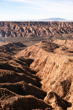 Aerial view of clay formations and canyons in a desert landscape in southern Spain showcasing unique geological patterns and textures