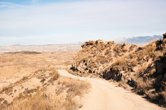 Dusty desert track winds through barren land in the Desierto de Gorafe near Granada, southern Spain