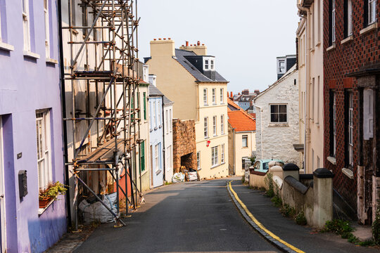 Narrow cobblestone street in St. Peter Port with warm light illuminating buildings