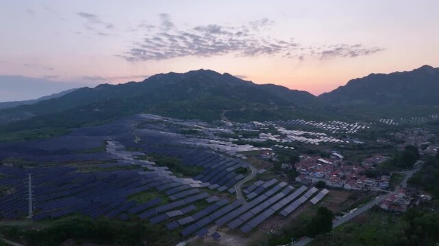 Solar photovoltaic power station on mountain slopes during sunset captured from aerial view