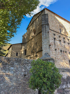 Monastery of San Jeronimo of Yuste stands in Caceres with stone walls and trees under a blue sky