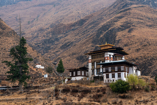 View of traditional building in Paro surrounded by mountains and trees during daytime