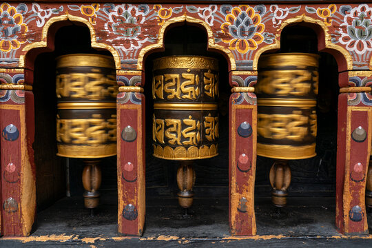 Prayer wheels spinning in Changangkha Lhakhang Temple, surrounded by traditional artwork in Thimphu, Bhutan